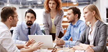 Group of business partners listening to colleague at meeting