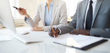 Cropped portrait of successful businesswoman pointing at computer screen while discussing project with African-American partner, copy space